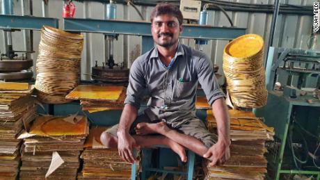 Kavala Krishnaiah, whose legs are not fully formed due to polio, makes disposable plates and bowls at Bollant Industries&#39; manufacturing unit.