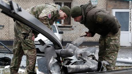 Police officers inspect the remains of a missile that landed in a street in Kyiv on February 24.