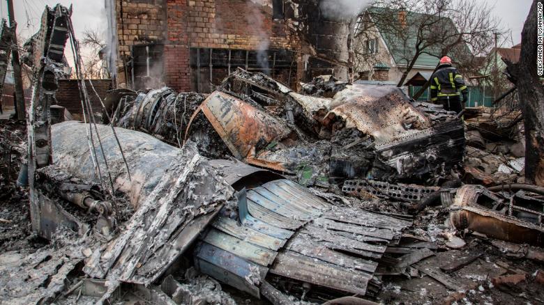 A Ukrainian firefighter walks between fragments of a downed aircraft in Kyiv, Ukraine, Friday, February 25, 2022. It was unclear what aircraft crashed and what brought it down.