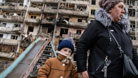 Onlookers examine the damage to a residential building after it was hit in a suspected Russian airstrike in the Ukrainian capital Kiev on February 25.