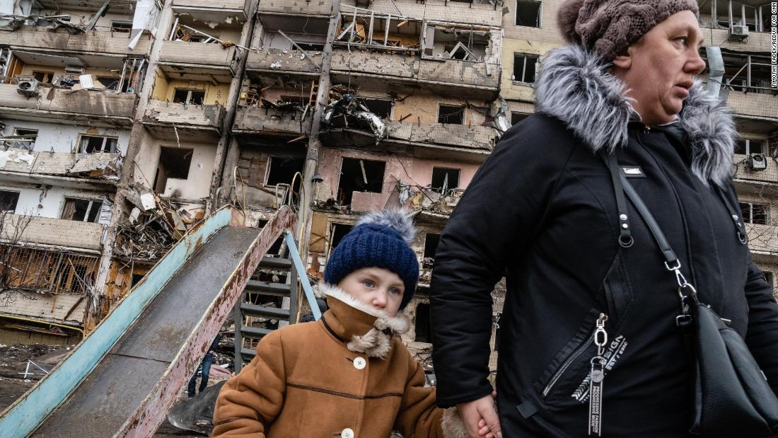 People walk past a residential building in Kyiv that was hit in an alleged Russian airstrike on February 25.
