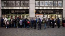 People queue outside a branch of Russian state-owned bank Sberbank to withdraw their savings and close their accounts in Prague on February 25, 2022, before Sberbank will close all its branches in the Czech Republic later in the day. - US President Biden was the first to announce sanctions, hours after Russian President Putin declared a &quot;military operation&quot; into Ukraine. The first tranche will hit four Russian banks -- including the country&#39;s two largest, Sberbank and VTB Bank -- cut off more than half of Russia&#39;s technology imports, and target several of the country&#39;s oligarchs. (Photo by Michal Cizek / AFP) (Photo by MICHAL CIZEK/AFP via Getty Images)