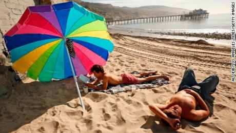 Matthew Bautista, 24, left, and his friend Bobby Kraemer, 27, right, spend the morning at Surfrider Beach in Malibu as a flurry of unusually warm weather continues April 30, 2021 at Surfrider Beach in Malibu, in California.