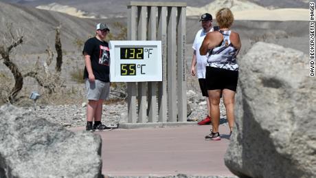 People pose in front of an unofficial thermometer reading 132 degrees Fahrenheit/55 degrees Celsius at the Furnace Creek Visitor Center on July 11, 2021 in Death Valley National Park, California. 