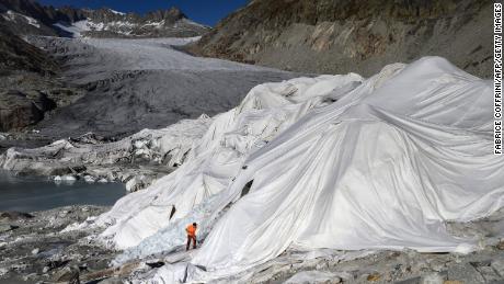 Un homme travaille dans les Alpes suisses au glacier du Rhône en octobre 2021, qui est partiellement recouvert de mousse isolante pour l'empêcher de fondre à cause du réchauffement climatique.