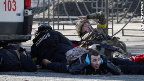 People take cover as an air raid siren sounds near a building damaged by recent shelling in Kiev, Ukraine, February 26.