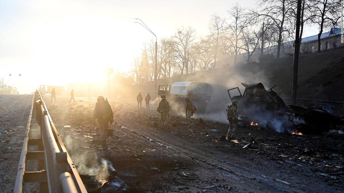 Ukrainian service members look for and collect unexploded shells after  fighting in Kyiv on February 26.