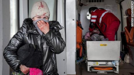 A woman reacts as paramedics perform CPR on a girl injured in shelling, at the Mariupol city hospital on February 27, 2022. The girl did not survive.