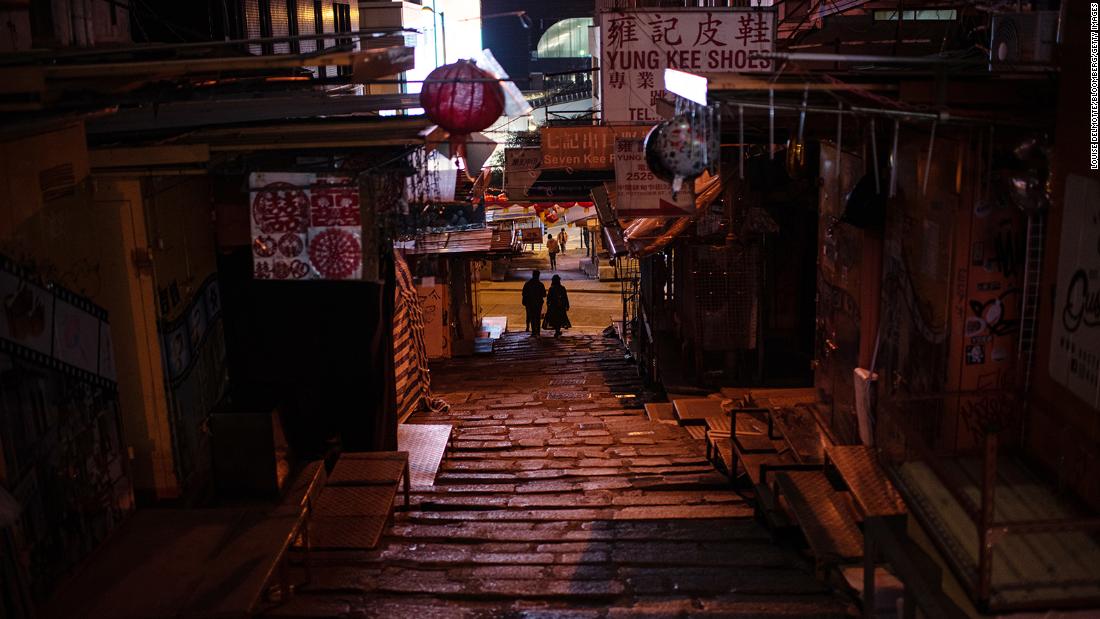 Pedestrians along a near empty street at night in Hong Kong, February 24, 2022.