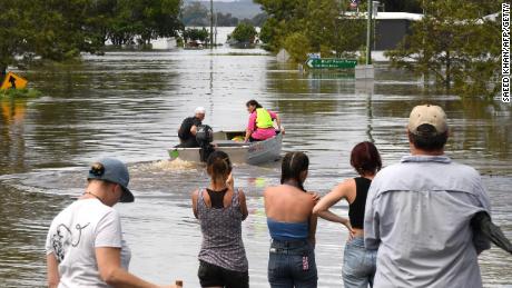 Des habitants se tiennent à côté d'une rue inondée dans la banlieue de Lawrence, à environ 70 kilomètres de la ville frontalière de Lismore en Nouvelle-Galles du Sud, le 1er mars 2022. 