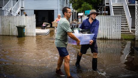 Residents carry belongings as they clean their homes in the flood-damaged suburb of Newmarket in Brisbane on March 1, 2022. 