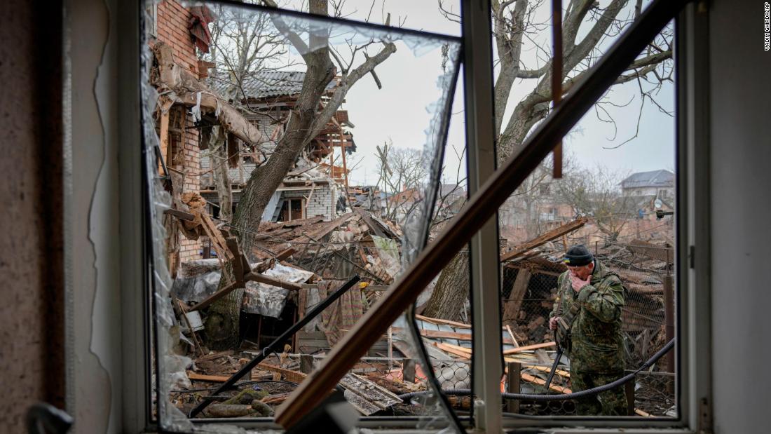 A member of Ukraine&#39;s Territorial Defense Forces inspects damage in the backyard of a house in Gorenka on March 2.