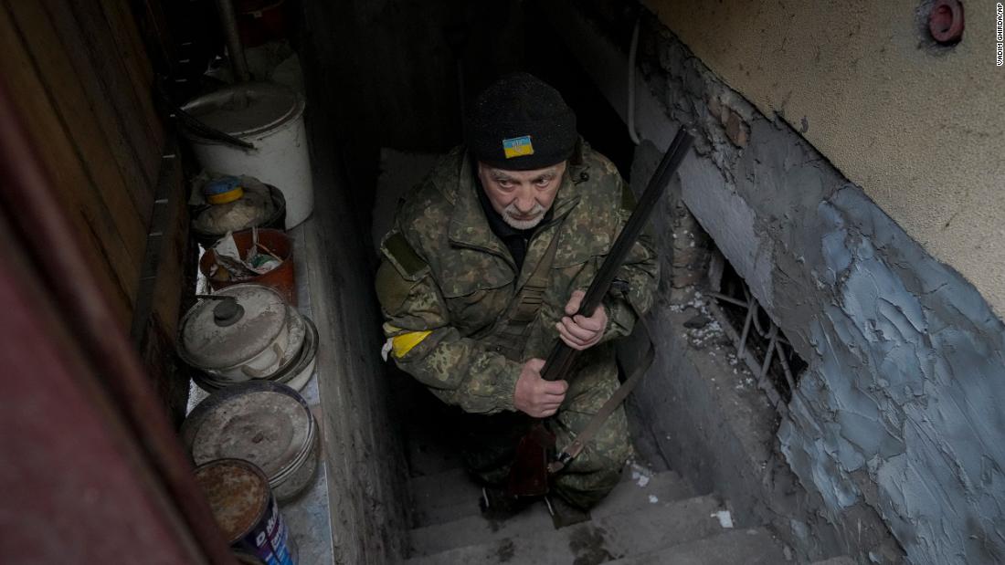 Andrey Goncharuk, a 68-year-old member of Ukraine&#39;s Territorial Defense Forces, clutches a hunting rifle March 2 while coming out of a small basement of a Gorenka house crowded with people seeking shelter from Russian airstrikes and shelling.