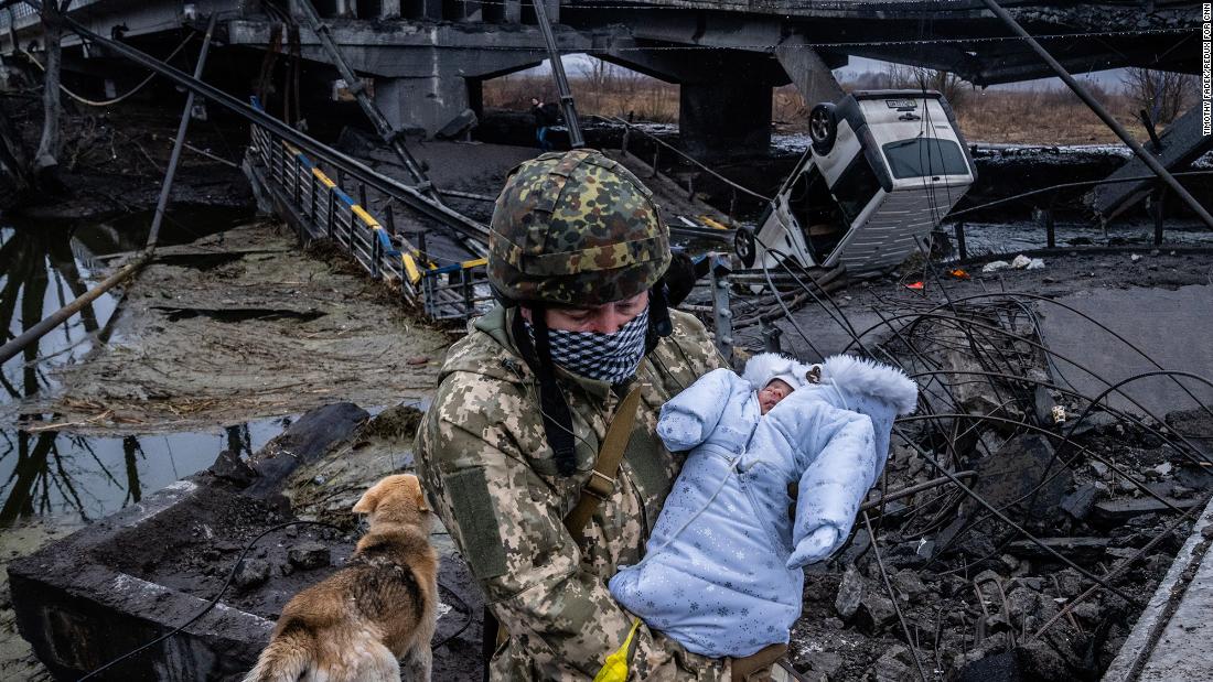 A Ukrainian soldier carries a baby across a destroyed bridge on the outskirts of Kyiv on March 3.