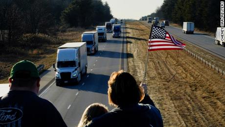 People hold a flag on an overpass in Brazil, Indiana on March 1, in support of a truck convoy bound for Washington, DC.
