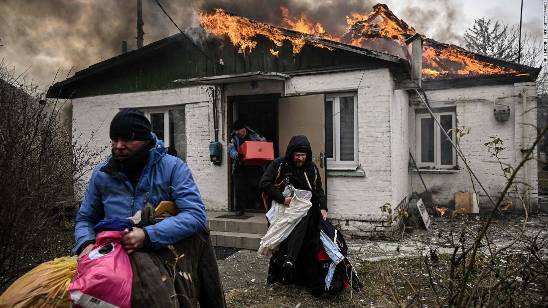 People remove personal belongings from a burning house after shelling in Irpin, Ukraine, on Friday, March 4.