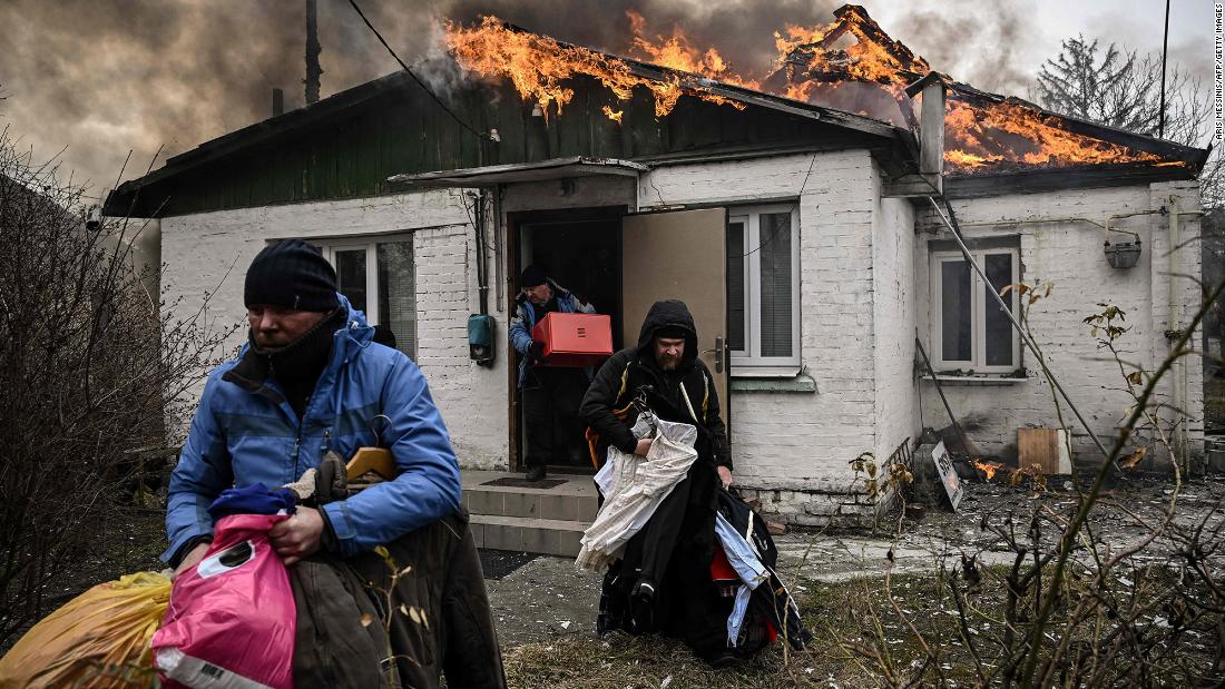 People remove personal belongings from a burning house after shelling in Irpin on March 4.