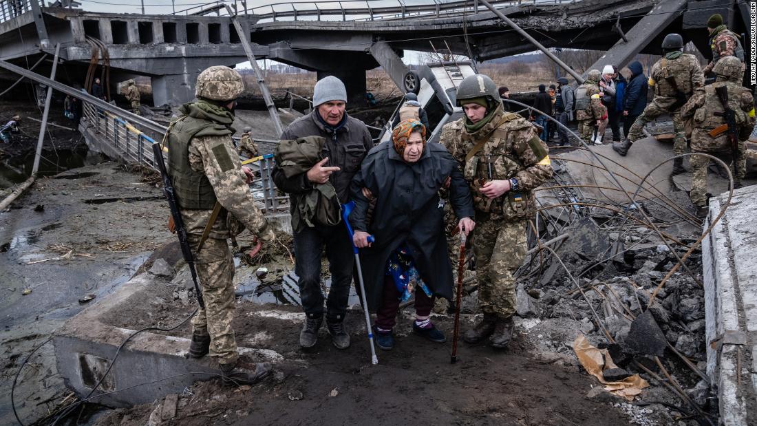 Residents are evacuated across a bridge from Irpin, on the outskirts of Kyiv, Ukraine, on Saturday, March 5. The bridge was previously destroyed by Ukrainian forces to prevent Russian forces from moving on central Kyiv.