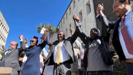 Arbery&#39;s family and their attorneys raise their arms in victory outside the federal courthouse in Brunswick, Georgia, after all three men involved in his killing were found guilty of hate crimes on February 22, 2022.