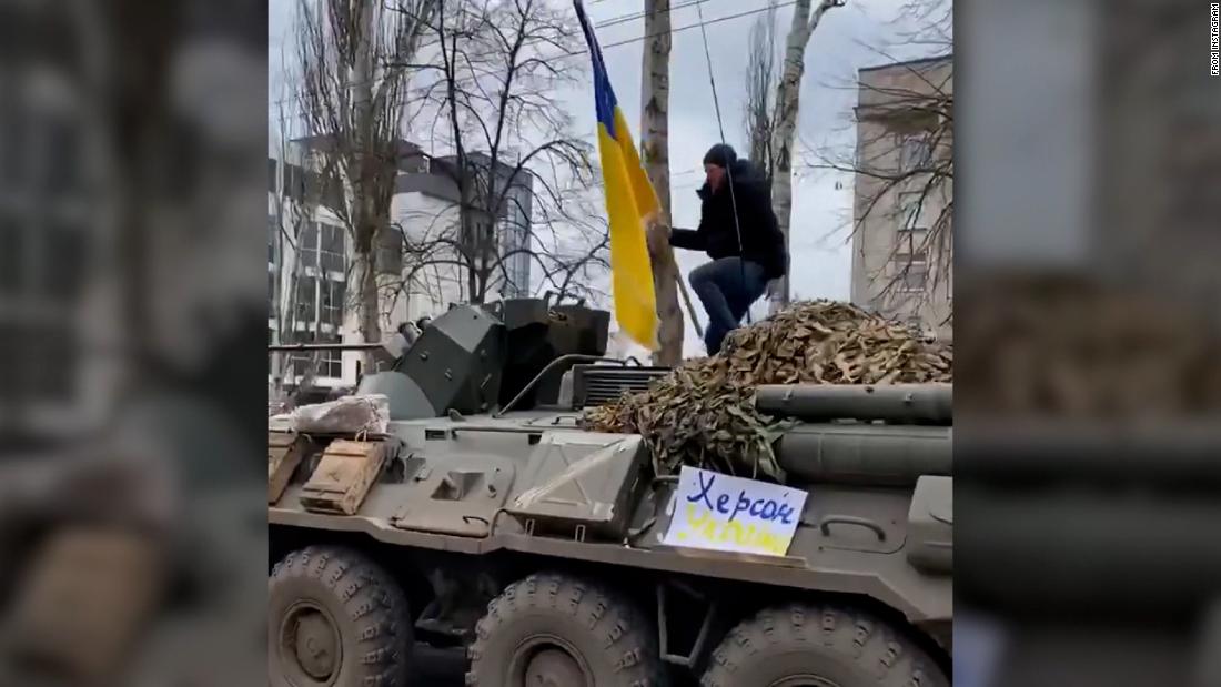 Man jumps on top of moving armored Russian vehicle while waving Ukrainian flag