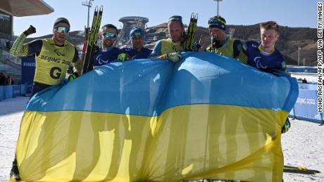 Ukrainian athletes celebrate with their country&#39;s flag after winning the mens middle distance vision impaired para biathlon.