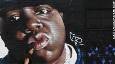 A woman passes by Brazilian artist Sipros&#39; mural of the rapper Biggie Smalls, featured on a wall in the Bushwick section of Brooklyn, New York, on June 6, 2019.