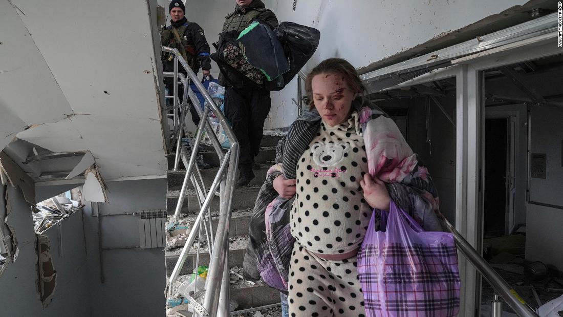 An injured pregnant woman walks down stairs to exit the hospital.
