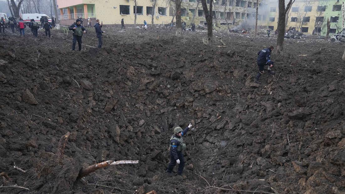 Ukrainian soldiers and emergency employees work at the site of the shelling.