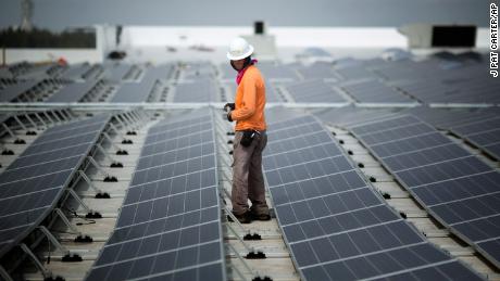 Un lavoratore cammina tra i pannelli solari installati sul tetto di un'IKEA a Miami nel 2014. A febbraio, IKEA aveva installato impianti solari nel 90% delle sue sedi negli Stati Uniti.