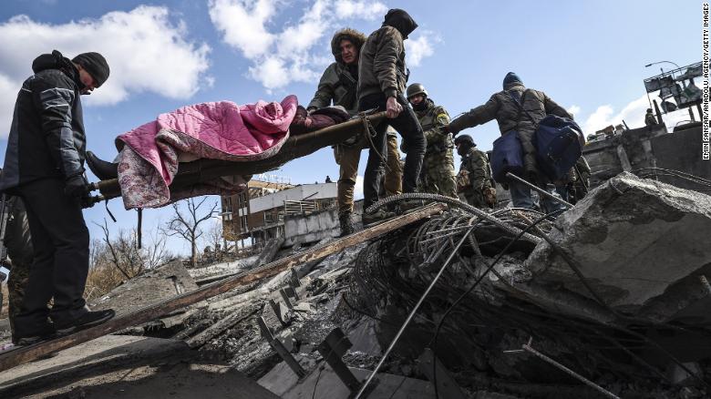 Men help carry an elderly woman who is fleeing Irpin, Ukraine, on Thursday, March 10.