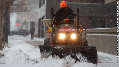 Eric Smith, with Paul Properties, uses a plow on a tractoro n March 10 to remove snow in downtown Topeka, Kansas.