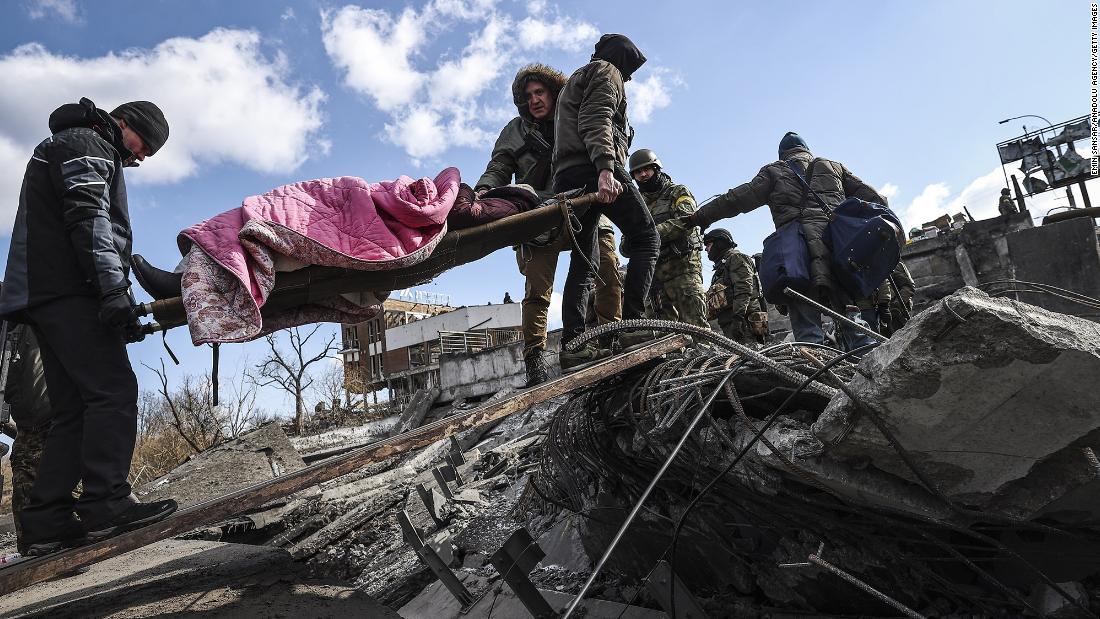 Men help carry an elderly woman who was fleeing Irpin, Ukraine, on Thursday, March 10.