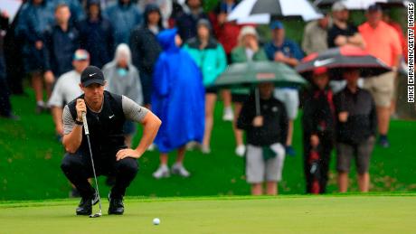 Rory McIlroy of Northern Ireland lines up his putt amid the rain.