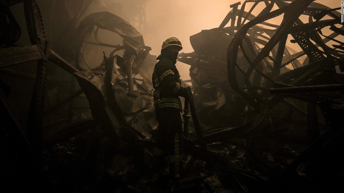 A Ukrainian firefighter drags a hose inside a food products storage facility which was destroyed by an airstrike in Kyiv, Ukraine, on Sunday, March 13.
