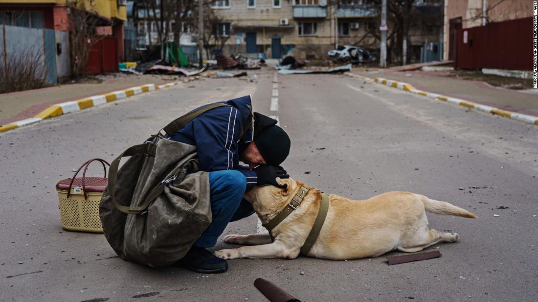 Andrei Kulik tries to comfort a dog who refuses to move from the middle of the road after the neighborhood in Irpin was bombarded by the Russian forces, March 13.