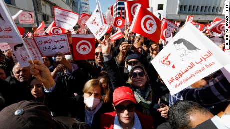Demonstrators hold placards and Tunisian national flags during a protest Sunday in Tunis against President Kais Saied&#39;s seizure of governing powers.