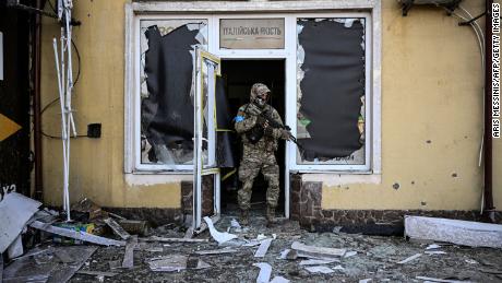 우크라이나 군인이 토요일 키예프에서 포격을 가한 후 손상된 건물에서 나오고 있습니다.