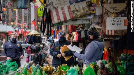 A police officer in New York&#39;s Chinatown hands out leaflets with information on how to report on hate crimes on March 17, 2021.