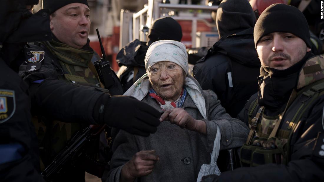 An elderly woman is helped by police officers after she was rescued from an apartment that was hit by shelling in Kyiv on March 15.