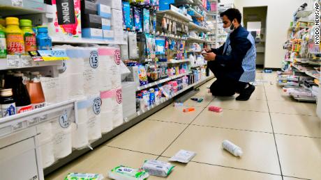 An employee clears products, which fell from shells in a convenience store in Iwaki, Fukushima, folllowing the earthquake.