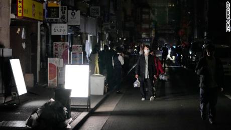 Menschen gehen während eines Stromausfalls in Tokio die Straße entlang.