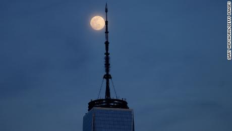 The worm moon, 98% illuminated, rises behind One World Trade Center in New York City on March 16, 2022, as seen from Jersey City, New Jersey.  