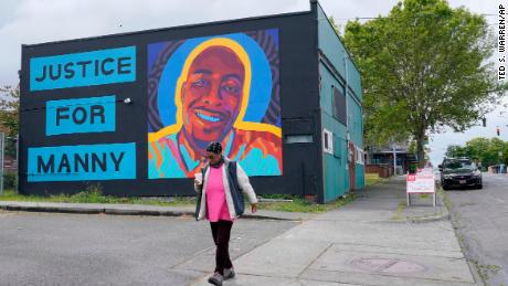 A woman walks past a mural honoring Manuel &quot;Manny&quot; Ellis, on Thursday, May 27, 2021, in the Hilltop neighborhood of Tacoma, Washington.