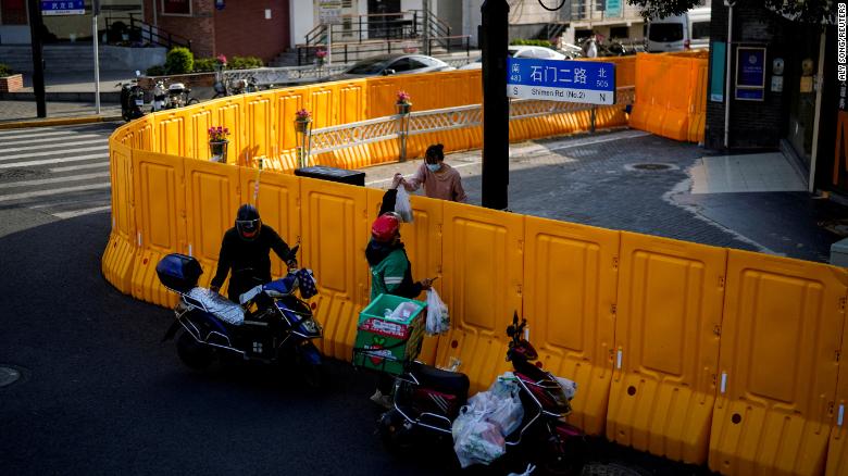 Một nhân viên giao hàng đưa thức ăn cho một phụ nữ qua hàng rào của một khu vực bị khóa ở Thượng Hải vào ngày 23 tháng 3 năm 2022.