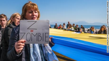 A woman holds a placard that reads &quot;Z = Zombie&quot; at a march in Naples, Italy.