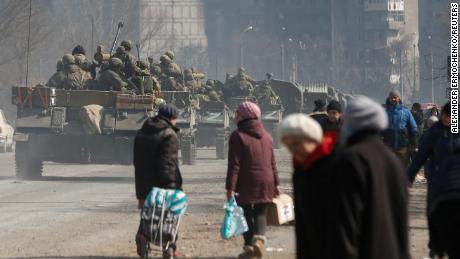 Service members of pro-Russian troops drive armoured vehicles past local residents in the course of Ukraine-Russia conflict in the besieged southern port city of Mariupol, Ukraine March 24, 2022. 