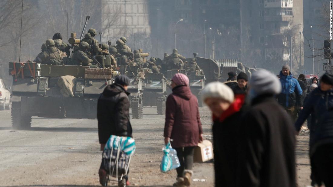 Pro-Russian troops drive armored vehicles past local residents into Mariupol on March 24.