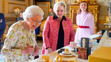 Queen Elizabeth II inspects hand-decorated porcelain at Windsor Castle.