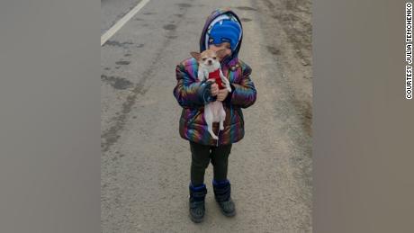 Five year old Milan keeps his spirits up with a friend&#39;s dog during stalemate traffic at a Poland checkpoint.