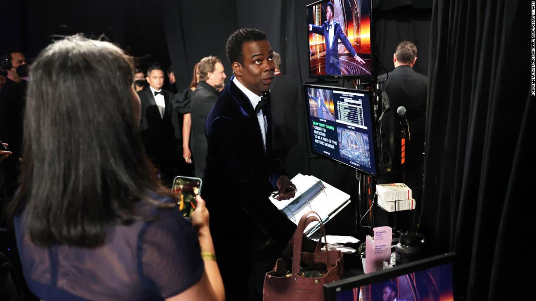 Chris Rock, backstage, watches Sean &quot;Diddy&quot; Combs on a monitor. Combs told the audience Smith and Rock would settle things &quot;like family&quot; later.